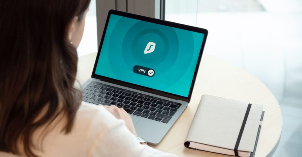 Mulher utilizando um laptop com a interface de um aplicativo de VPN